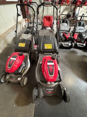 Trois tondeuses à gazon sont alignées les unes à côté des autres dans un garage