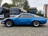 a blue sports car parked in a lot with buses in the background
