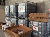 de nombreux conteneurs et cartons dans un entrepôt, avec des cartons posés à même le sol