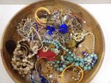 a wooden bowl filled with assorted jewelry on a table