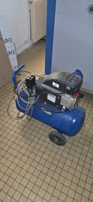 a blue air compressor sitting on the floor in a room