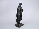 une statue noire représentant une femme tenant un livre, posée sur un socle en marbre