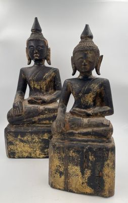 two statues of buddhas sitting on blocks on a white background