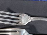 two forks that are sitting on a black cloth