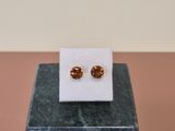 a pair of earrings sitting on top of a marble block