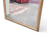 a mirror that is sitting on the floor in front of a red curtain