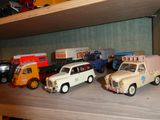Plusieurs camions miniatures sont alignés sur une étagère dans une pièce