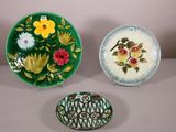 trois assiettes décoratives ornées de fleurs et de feuilles, posées sur une table