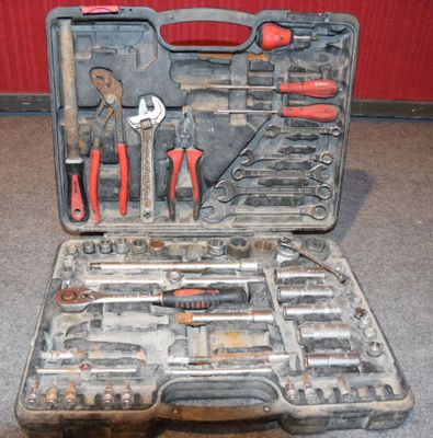 une caisse d'outils avec des outils à l'intérieur, posée sur le sol