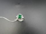 une bague en émeraude et diamant sur une surface noire