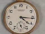 a gold pocket watch with a white face and numbers on it