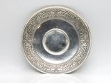 an antique silver plate on a white surface with a reflection