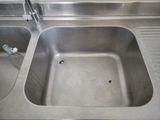 a stainless steel sink in the corner of a bathroom