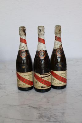 three bottles of beer sitting on top of a marble counter top