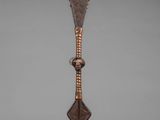 a bronze sculpture of a spear on a wooden base