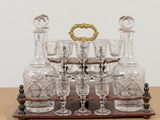 bottles and glasses on a wooden stand on a table
