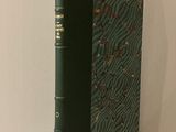 un vieux livre à la couverture verte posé sur une table blanche