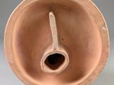 a clay vase with a handle in the middle of it