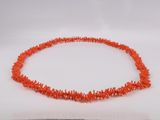 an orange necklace with a strand of coral beads on a white surface
