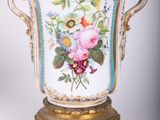 a vase with flowers painted on it sitting on a stand