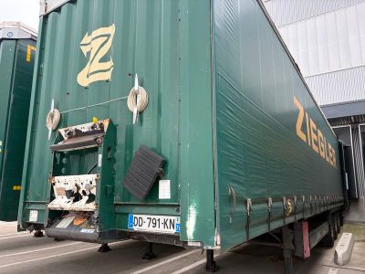 un semi-remorque vert garé devant un immeuble