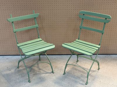 pair of green metal folding chairs sitting next to each other