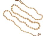 un gros plan d'un collier composé de perles et d'une croix suspendue à une chaîne