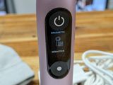 a pink electric toothbrush sitting on a wooden table