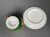 two white and green cups and saucers on a gray surface