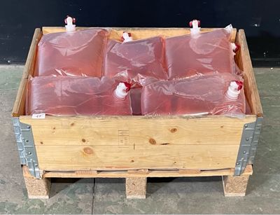 une caisse en bois remplie de bouteilles contenant un liquide rouge, posée sur une palette