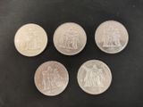 six different british pound coins on a black surface