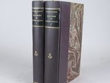 two books are sitting on top of each other on a white surface