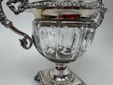 a silver cup on a stand with a red apple in it