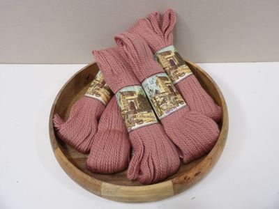 three skeins of pink yarn in a wooden bowl on a white surface
