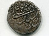une vieille pièce d'argent portant une inscription en arabe sur un fond blanc