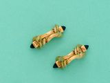une paire de boucles d'oreilles en forme de crayons dorés et noirs sur fond turquoise