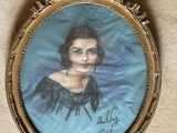 an old picture of a woman in a blue dress is hanging on a wall