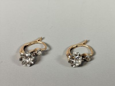 a pair of gold and diamond earrings on a white surface