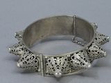 an antique silver bracelet with filigree design on a grey background