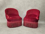 une paire de fauteuils en velours rouge aux pieds ornés de franges