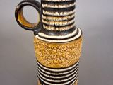 a black and white striped vase with a brown handle