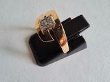 a gold ring with a diamond on it on a black stand