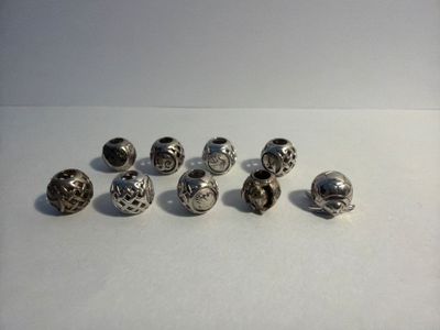 several silver metal beads sitting on top of a white surface