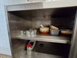 une armoire en acier inoxydable sur laquelle sont posés de la vaisselle et des tasses