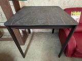 une petite table au plateau noir posée sur une chaise rouge