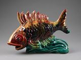 a ceramic fish that is sitting on top of a wave