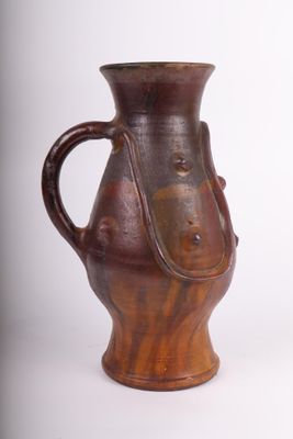 un vase brun posé sur une surface blanche