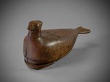 an old wooden bird sitting on top of a white surface