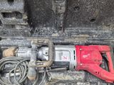 a red drill in a tool case with a cord