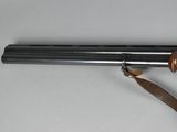 a close up of a gun with a wooden handle on a white surface